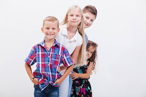 The  happy smiling teenagers standing arm in arm on white background.