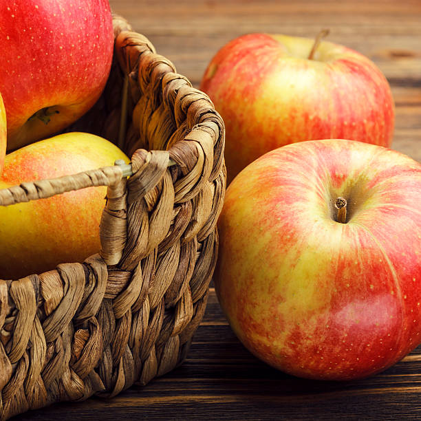 istock Red apple and basket on wooden background 486310347