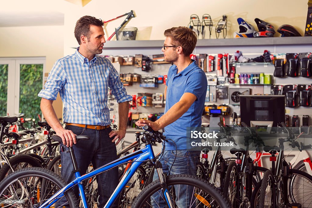 Man buying bicycle Man buying a bicycle in bike store, talking with shop assistant. Bicycle Stock Photo