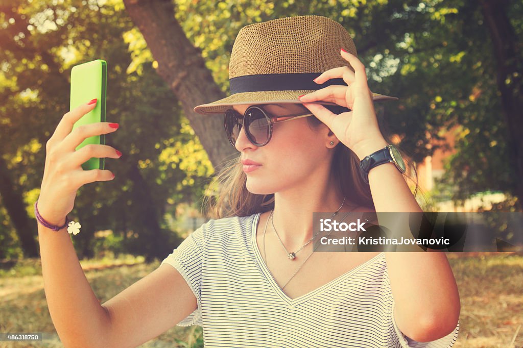 Young woman taking a selfie with cellphone на открытом воздухе. - Стоковые фото 2015 роялти-фри Young woman taking a selfie with cellphone на открытом воздухе. - Стоковые фото 2015 роялти-фри