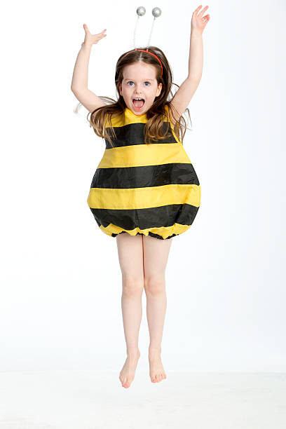 Little Girl in a Bumble Bee Costume Little girl in a bumble bee costume posing in midair against a white background bee costume stock pictures, royalty-free photos & images