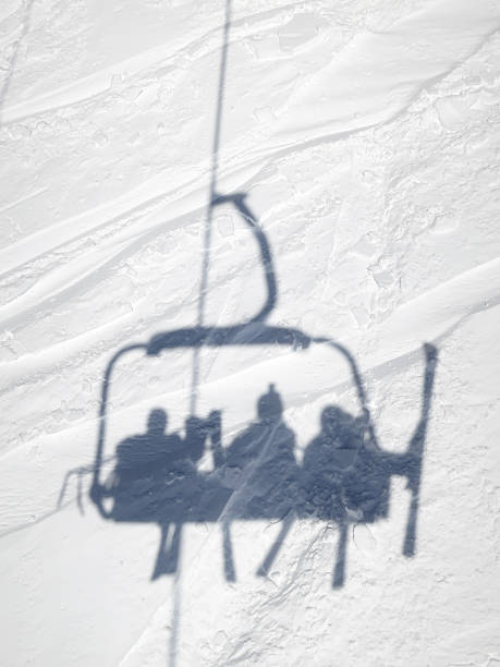 Shadow of skiers in ski lift chair stock photo