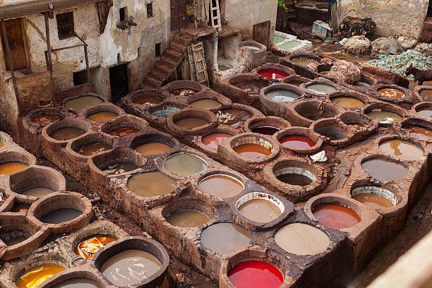 Man working in traditional Moroccan leather tanneries, medina Fez, Morocco. Fez is the second largest city of Morocco, and is a UNESCO World Heritage Site. The city has been called the \