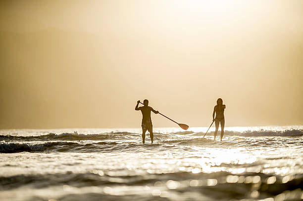 スタンドアップパドルボートの夕暮れ - women sensuality surfing water sport ストックフォトと画像