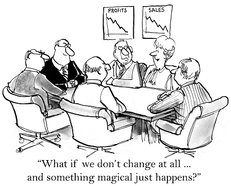 Business cartoon showing six businesspeople in a meeting.  Charts not he wall show declining sales and profit.  Businesswoman says, 