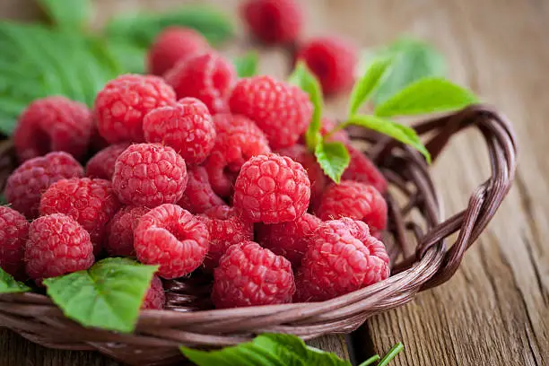 Fresh organic ripe raspberry with leaf in basket,  selective focus