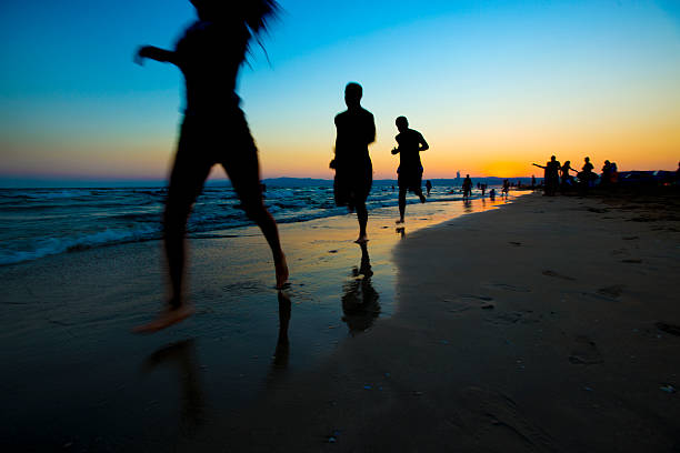 Visitors enjoy a sunny day at Isla Canela beach, with one person swimming in the sea while another strolls along the sandy shore.
