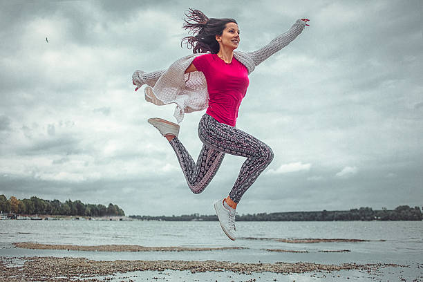 幸せな若い女性を実行、ジャンプ、ビーチ - arms outstretched teenage girls jumping flying ストックフォトと画像