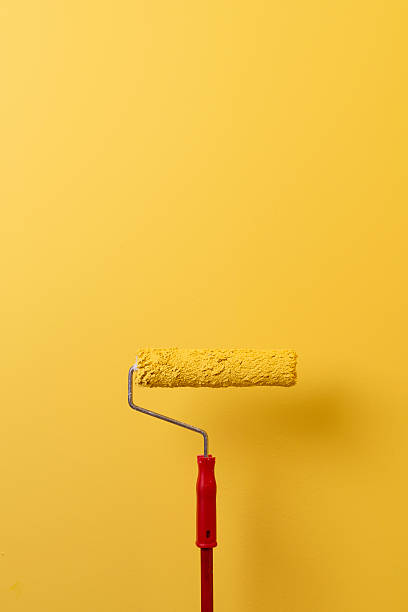 Paint Roller Painting The Wall In Yellow