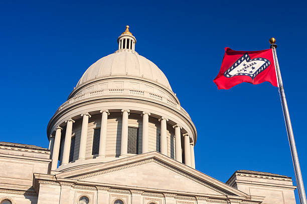 The Arkansas State Capitol building in Little Rock with the State Flag in the foreground.