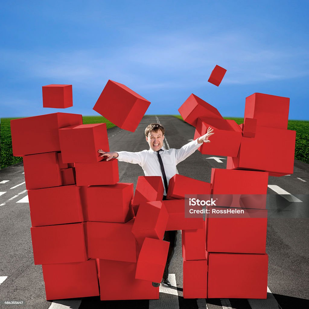 Business man breaking the wall of carton boxes Business man breaking the wall of carton boxes on the road Bizarre Stock Photo