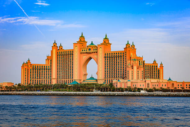 Atlantis, The Palm, Luxury Hotel in Dubai, UAE Dubai, United Arab Emirates - April 04, 2012:  Atlantis, The Palm, the luxury five star hotel located on the outer crescent of the man made island, the Palm Jumeirah in the Arabian Gulf city of Dubai, in the United Arab Emirates. In the foreground the waters of the Persian Gulf and date palms transplanted to create a man made garden in front of the hotel. Some traffic and people can also be seen. Photo shot from a boat at an off-shore location, in the afternoon sunlight.  Horizontal format; copy space. atlantis the palm stock pictures, royalty-free photos & images