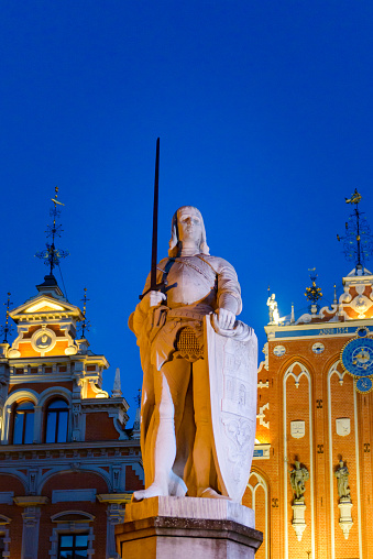 Riga, Latvia- August 15, 2015:  Statue Of Roland In Riga at dusk With The House Of The Blackhead's And St. Peter's Church In The Background.