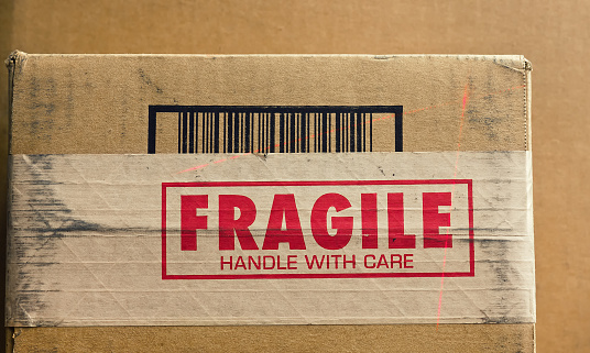 Fragile sign on shipping box with barcode being read by a thin red laser.