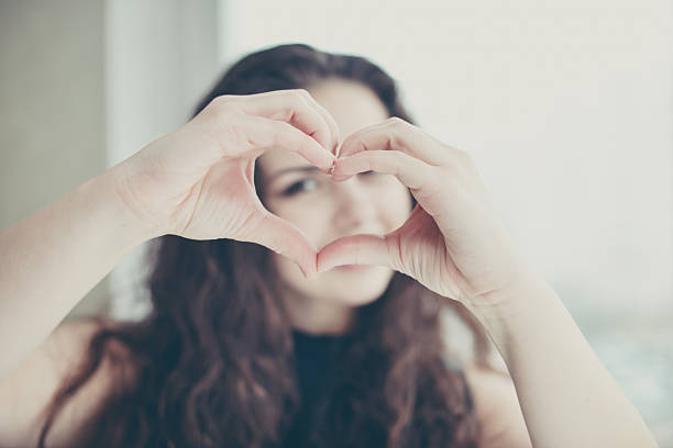 istock Beautiful young woman doing a heart shape with her hands 486360176