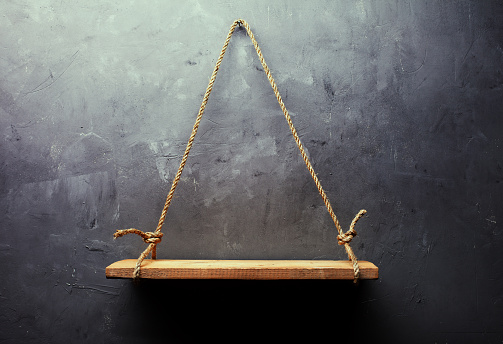 Empty old wood shelf hanging on rope on textured wall background