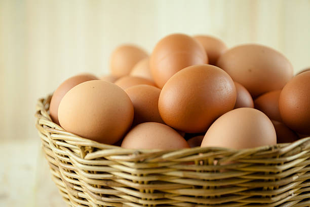 voller eier legen sie in einem weidenkorb - breakfast easter yellow easter egg stock-fotos und bilder