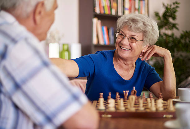 grand-père et de grand-mère jouant aux échecs pour la relaxation - senior adult leisure games playing care photos et images de collection