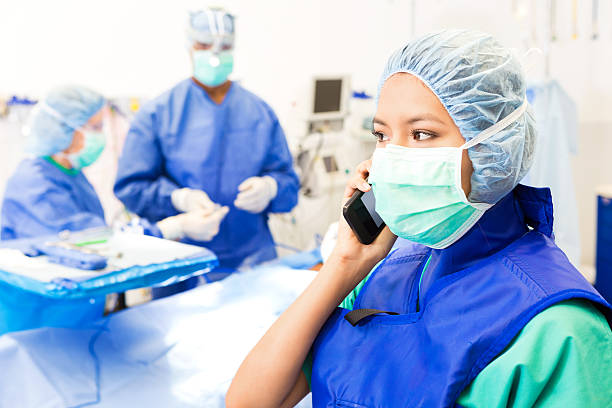 surgical technician or nurse taking phone call in operating room - nurse on phone serious bildbanksfoton och bilder