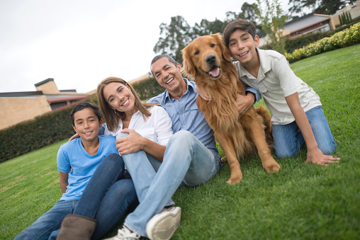 Happy Latin American family with a dog spending time together and sitting at the backyard of their house