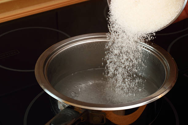 注ぐ砂糖片手鍋に水を沸騰する - syrup ストックフォトと画像