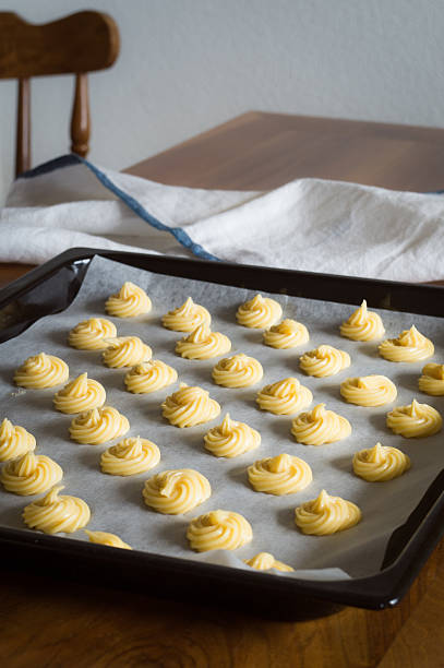 istock Unbaked cream puffs on parchment-lined baking sheet 486381738