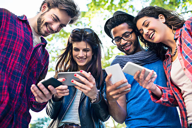 Connected Four friends checking their mobile phones at the same time. photo messaging stock pictures, royalty-free photos & images
