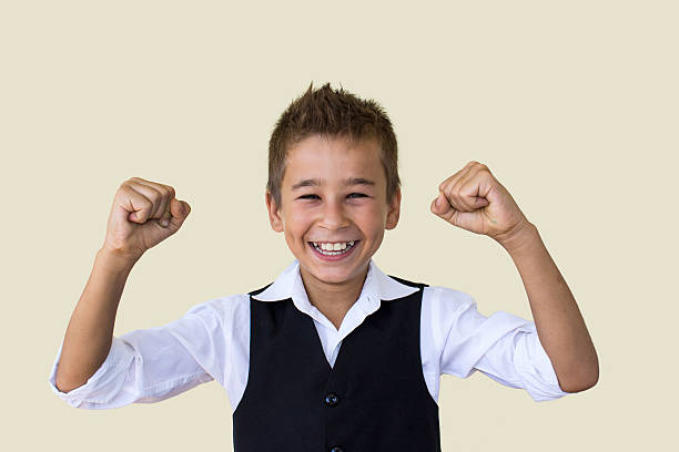 istock Little boy cheering his success in suit against colored backgrou 486391242