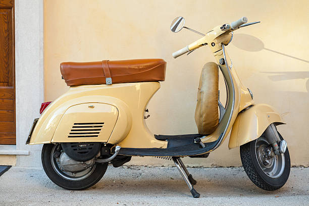 Gaeta, Italy - August 19, 2015: Classic yellow Vespa scooter stands parked near the wall