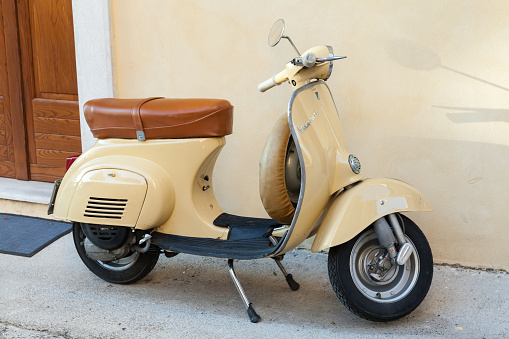 Gaeta, Italy - August 19, 2015: Classical yellow Vespa scooter stands parked near the wall