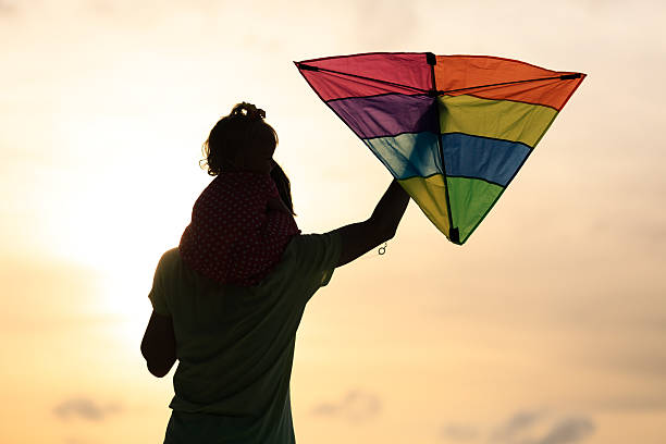 istock father and little daughter flying kite at sunset 486394156