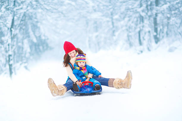 matki i maluch córkę się sledge ride w snowy park - sleding zdjęcia i obrazy z banku zdjęć