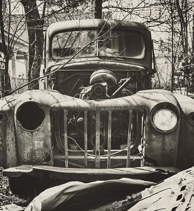 A 1950's pickup truck missing many parts. Toned black and white.