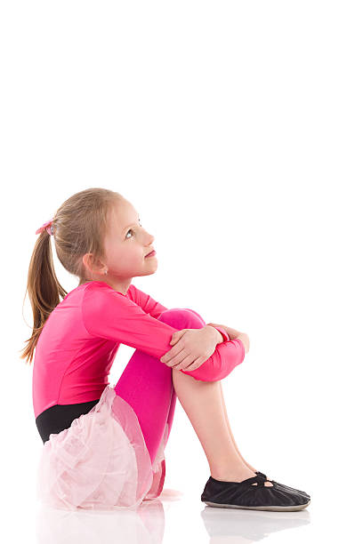 Little girl sitting on the floor, Side view.