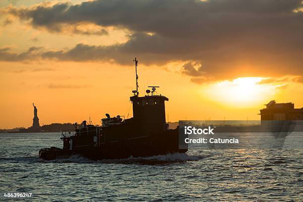 Tugboat Heads Towards New York From Liberty Island At Sunset Stock Photo - Download Image Now