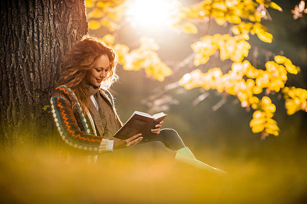 istock Young woman relaxing while reading a book in autumn. 486400758