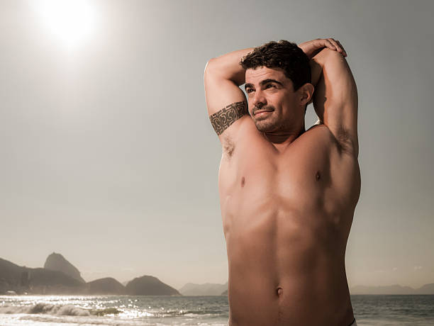 istock Muscular build man stretching his arm on the beach. 486400826