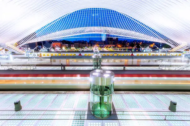 futuristic railway station illuminated at night with motion blurred trains, Liege, Guillemins, Belgium