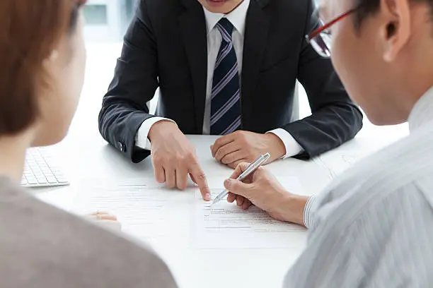 Photo of Young couple signing renting contract with real estate agent