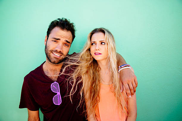 Funny man embracing angry young woman on green background