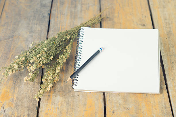 istock vintage notepad with dry flowers on wood table, 486414974