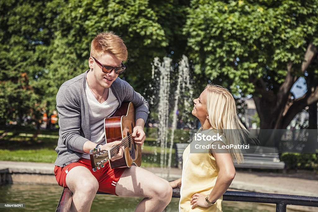 Young friends playing guitar outdoors Young friends playing guitar outdoors. Acoustic Guitar Stock Photo