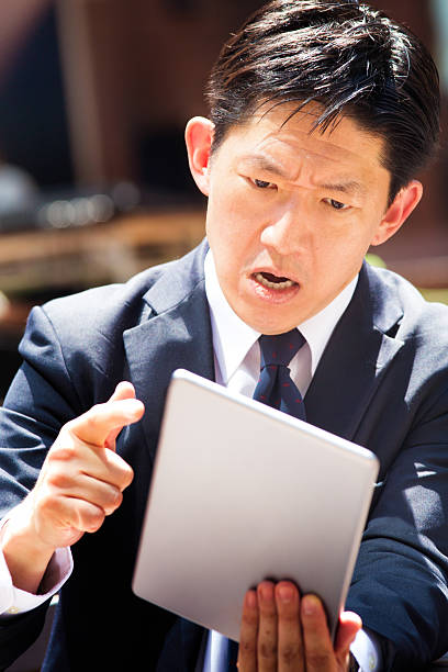 istock Angry Japanese office worker  on video conference threatens tablet 486416714