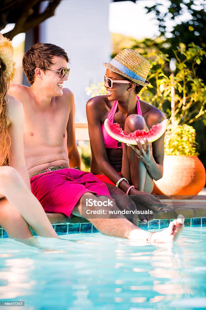 Interracial couple laughing by swimming pool Multi-ethnic couple enjoying by swimming pool Adult Stock Photo