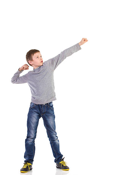 Punch the air Boy posing with fist raised and looking away. Full length studio shot isolated on white. whole punch stock pictures, royalty-free photos & images