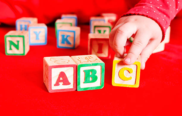 Child puts cubes ABC Child puts cubes ABC on red sofa b c stock pictures, royalty-free photos & images