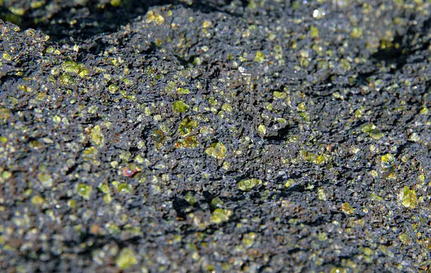 Green sand crystals of Olivine are adhered to rocks on the Green Sand Beach of the Big Island of Hawaii.