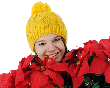 Closeup of a  pretty teen girl, bundled for winter, happily carrying a bundle of red poinsettias.  On a white background.