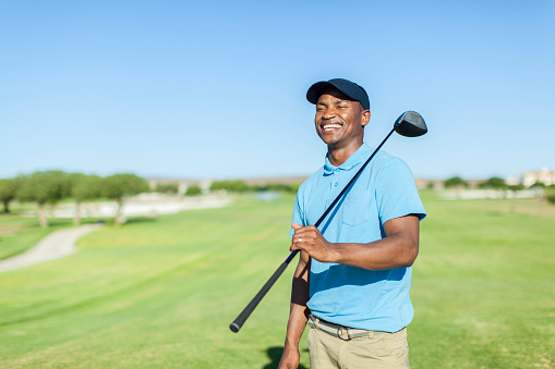 African golfer holding his driver club on his shoulder, laughing. Langebaan, Western Cape, South Africa