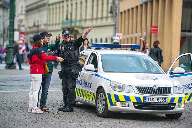 Prague, Czech Republic - May 3, 2015: Policeman showing direction to Asian tourists in Prague